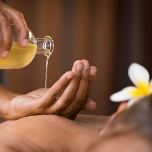 Hand pouring oil getting ready to massage a client with the body oil