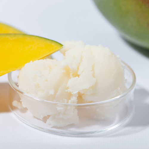 Mango body butter in a clear dish with a slice of mango on a white background